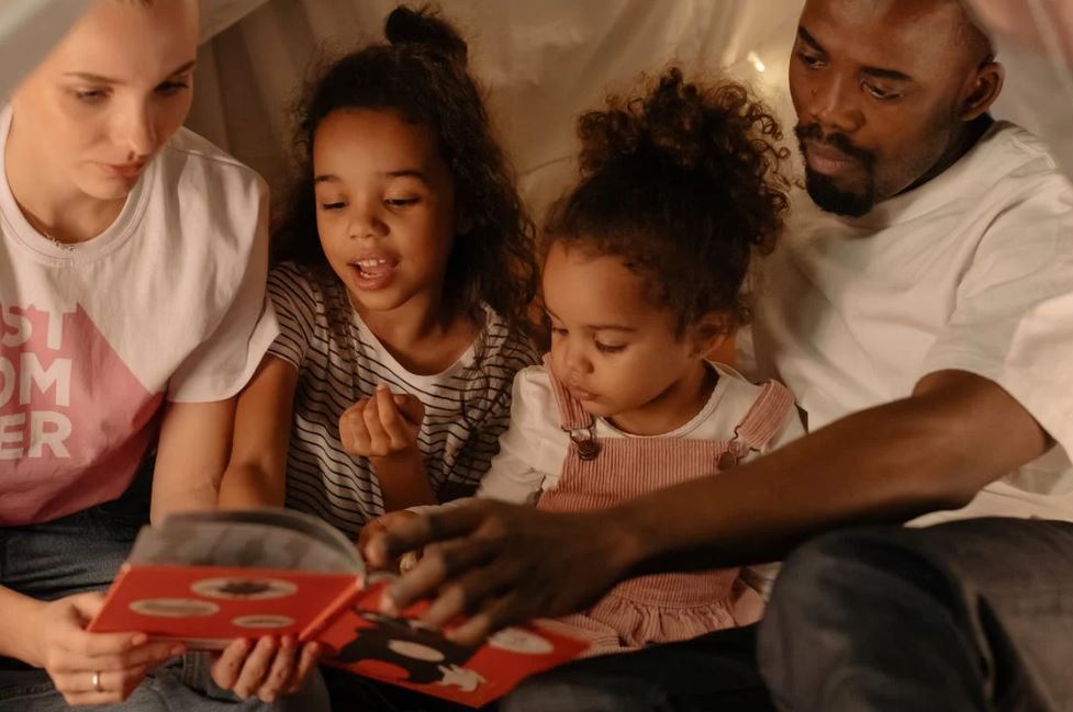 parents reading a book to their children